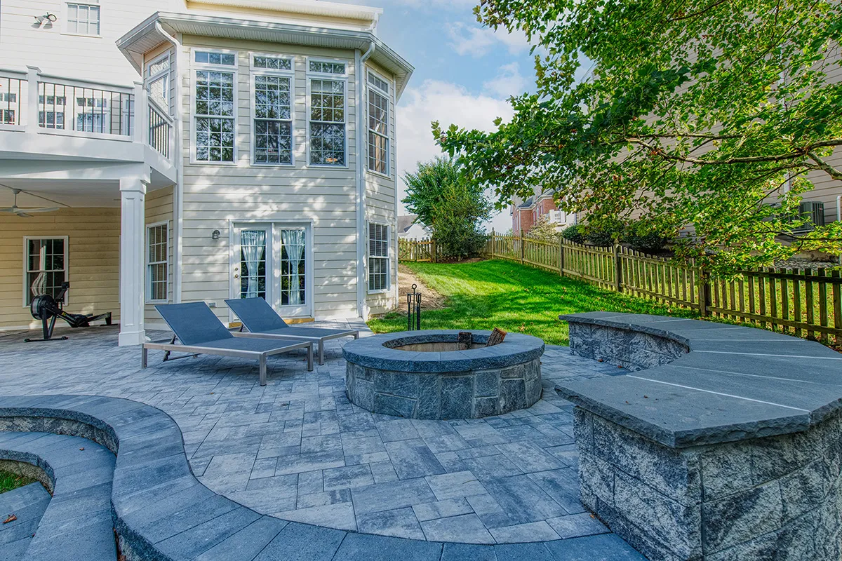 Outdoor living space transformation by an expert landscaper in Johnston, IA, incorporating permeable paver patios and rain gardens for municipal stormwater compliance.